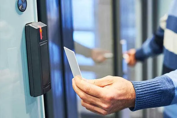 Hand presenting an access card to a wall-mounted reader