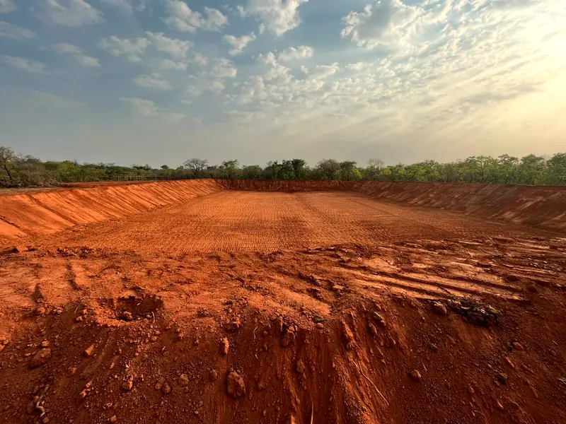 Freshly excavated red earth pond at a mineral processing site