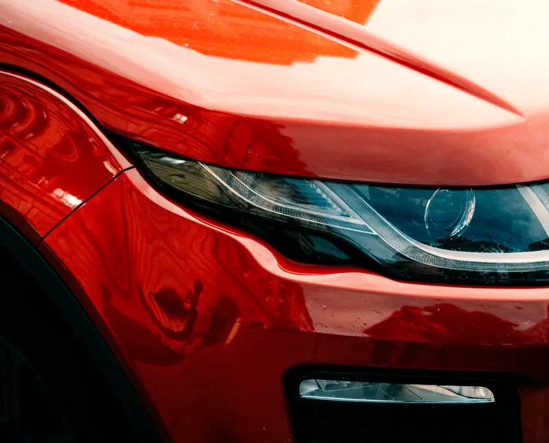 Close-up of a red car's headlight and bodywork