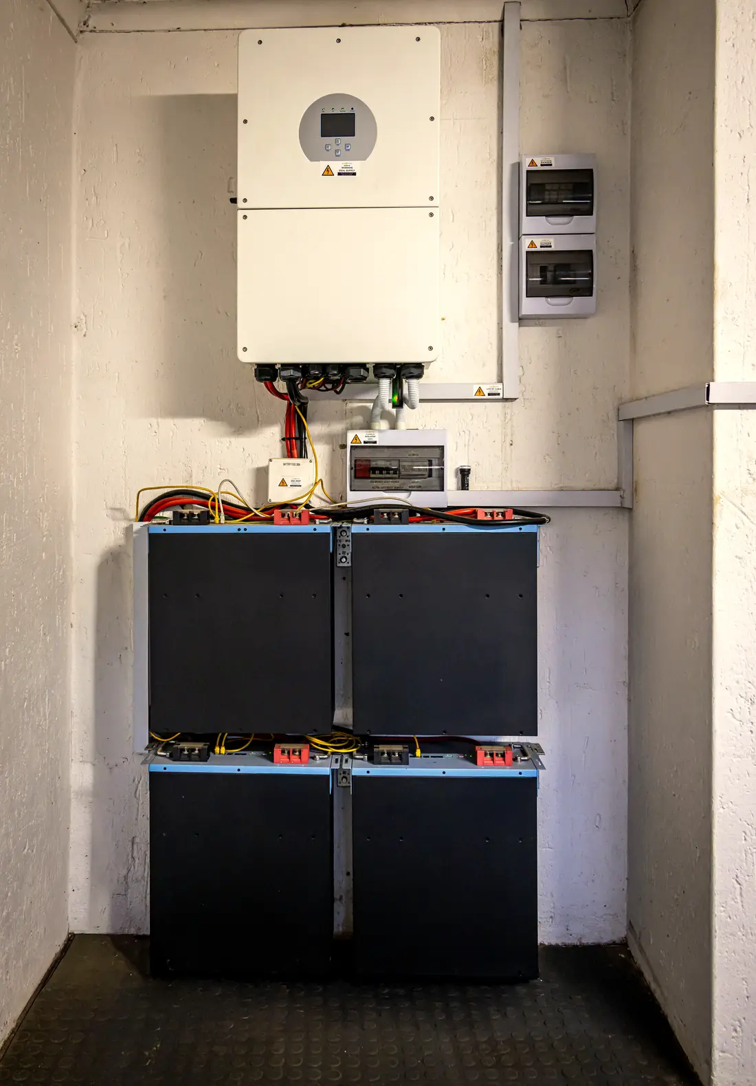 Wall-mounted hybrid inverter above four lithium battery modules